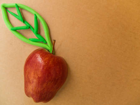 red apple with Plasticine green leaf  on isoled brown backgroundの写真素材