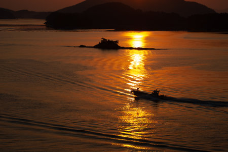 Silhouette of a man in a boat on the sea at sunsetの写真素材