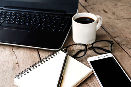 Laptop, Notebook, Smart Phone and Glasses on Wooden Desk