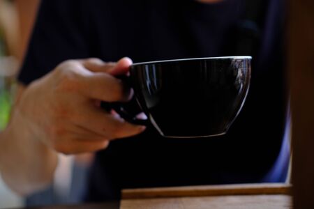 Hand Hold a Cup of Coffee. Menu Drink for Relax on Wood Table Texture and Space for your text....