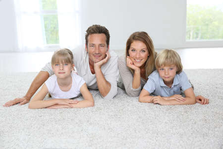 Happy family of four laying on carpet at home Happy family of four laying on carpet at home