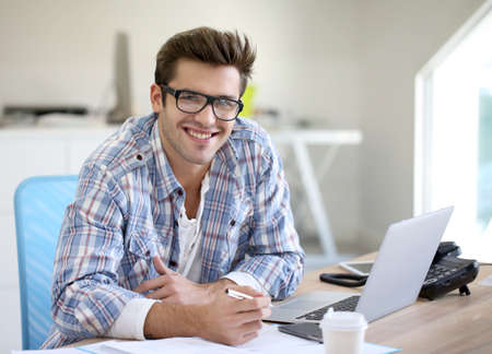 Young man in office working on laptop computer Young man in office working on laptop computer