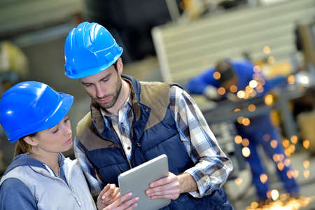 Engineers in steel factory working on digital tablet Engineers in steel factory working on digital tablet