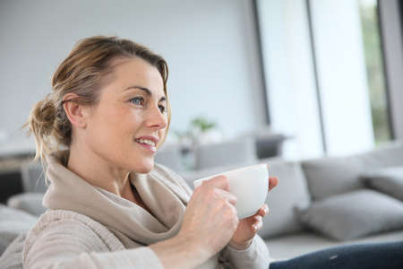 Mature woman in sofa drinking hot coffee Mature woman in sofa drinking hot coffee