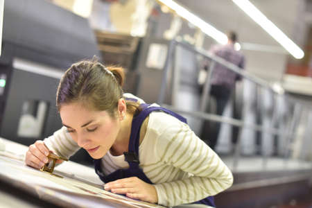 Woman in printing house using magnifying glass Woman in printing house using magnifying glass