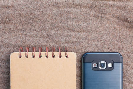 notebook page and smartphone on brown fabric, upper empty space fot textの写真素材