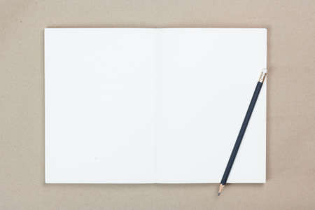 open book and black penciil on brown blackground