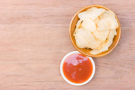 potato chips on bowl and catchup place on right side of wood tableの写真素材
