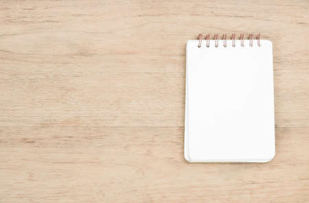 white opened notebook place on brown wood texture, empty area on left of image for copy space, from top viewの写真素材