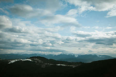 Cloudy sky above snowy forest and mountains