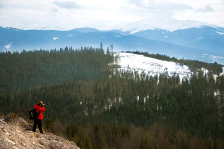Photographer with mountains in cloudy sky and forest backgroundの写真素材
