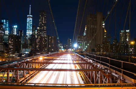 USA. New York City. Night. Traffic on the Brooklyn bridge and a view of the skyscrapers of Manhattanの写真素材