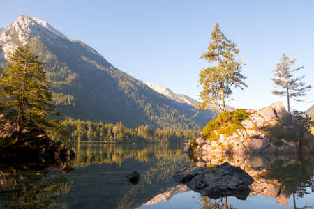 Germany. Mountain forest lake Hintersee. Water mirror, the cloudless sky and the dawnの写真素材