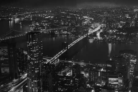 Buildings, skyscrapers, streets, the Brooklyn and Manhattan bridges at night in New York City. Aerial view. Black and whiteの写真素材