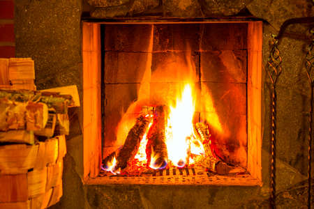 Hot fire in the fireplace. A bundle of firewood in the basketの写真素材