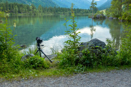 Germany. Mountain forest lake Hintersee. Summer overcast day. Tourists on boats. Camera on a tripod at the water's edgeのeditorial素材