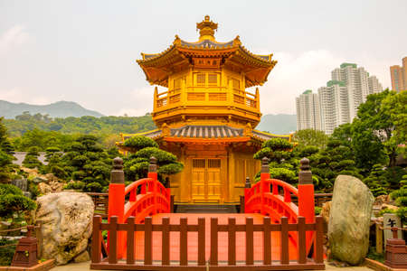 China. Hong Kong. A cloudy day in Nan Lian Garden. Golden pavilion in the background of skyscrapersのeditorial素材