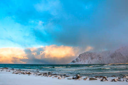 Norway. Lofoten. Winter. Ocean surf between the mountains. Colored clouds over the wavesの写真素材