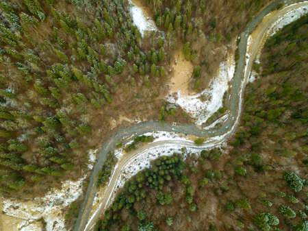 Spruce forest in the beginning of winter. Little river. A snow on the ground. Top view vertically downの写真素材