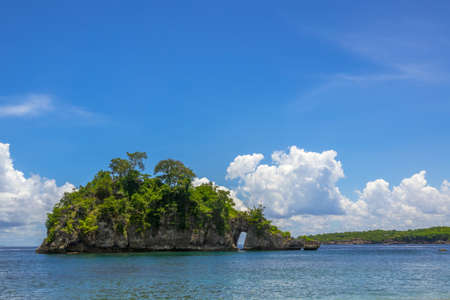 Indonesia. Rocky island with forest, sunny blue sky and beautiful cloudsの写真素材