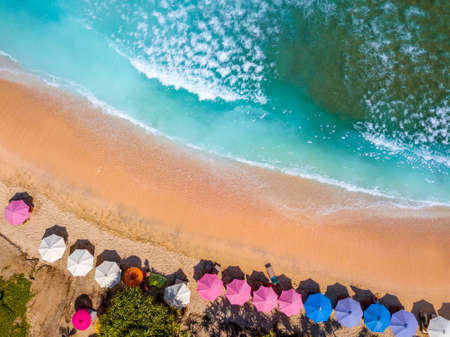 Indonesia. Sandy beach on one of the small tropical islands. Emerald water and sun umbrellas. Aerial view vertically downの写真素材