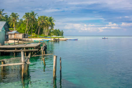 Indonesia. Several buildings and boats on the shore of a tropical island. The vast ocean to the horizonの写真素材