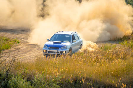 Summer sunny day. Blue car is turning the dirt road. A lot of dustのeditorial素材