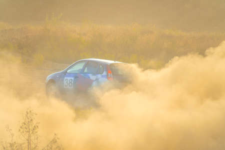 Sunny summer day. Color car is turning the dirt road. A lot of dustのeditorial素材