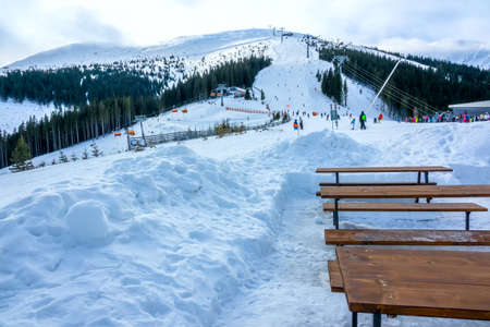 Winter Slovakia. Ski resort Jasna. Overcast. Empty wooden benches and tables near ski slopeの写真素材