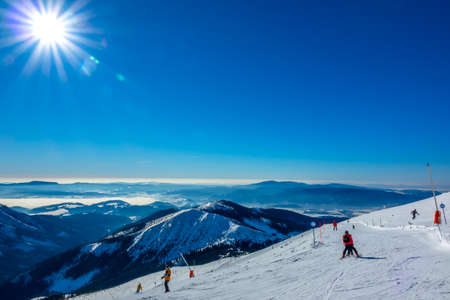 Winter Slovakia. Ski resort Jasna. Panoramic view from the top of the snow-capped mountains and ski slope with skiersの写真素材