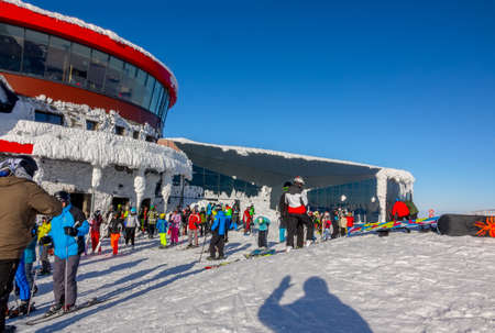 Slovakia, Jasna. Snow covered ski lift station on top of the mountain. Sunny cloudless day. Crowd of skiers and snowboardersのeditorial素材