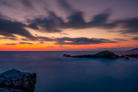 Rocky shore of the sea. Colorful sunset in the sky with cloudsの写真素材