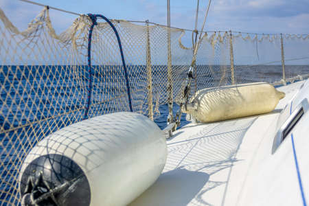 Board a sailing yacht in sunny weather. Two fenders and a mesh fenceの写真素材