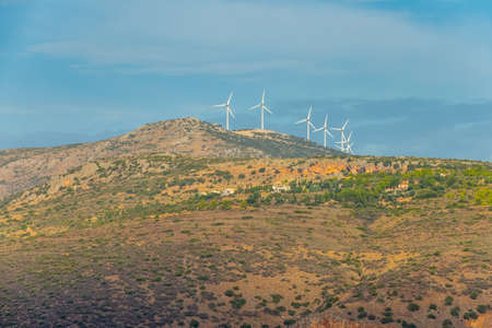 Summer day on the hills in Greece. A small village and several wind farms on top of a mountainの写真素材