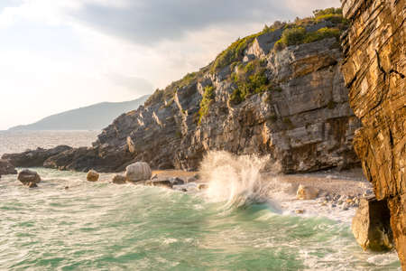 Small beach on a rocky seashore. Summer evening and surf sprayの写真素材