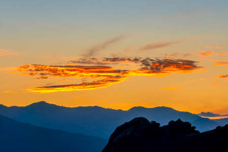 Greece. Silhouettes of the mountain peaks. Golden sky with clouds after sunsetの写真素材