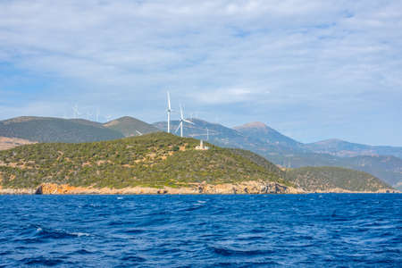 Greece. Hilly coast of the Gulf of Corinth in sunny day. Old lighthouse building and many wind farmsの写真素材