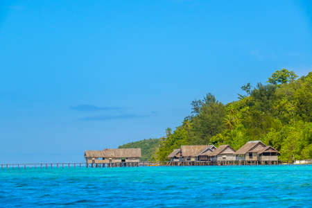 Indonesia. Tropical island in the early evening. Long wooden jetty and several huts on stilts in the waterの写真素材