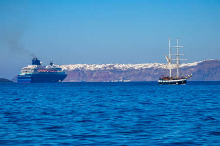 Greece. Sunny day off the coast of Santorini. Old three-masted ship and multi-deck cruise shipの写真素材