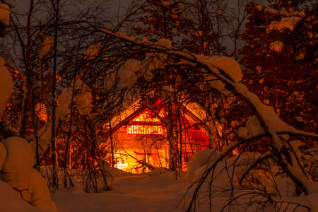 Winter Finland. Thick forest and a lot of snow. Small wooden house and night lightingの写真素材