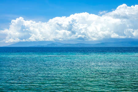 Sunny day in Indonesia. Turquoise water of calm ocean. Surprisingly beautiful clouds over the distant shoreの写真素材