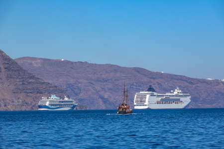 Greece. Sunny day off the coast of Santorini. Two cruise multi-deck ships and old three-masted shipの写真素材