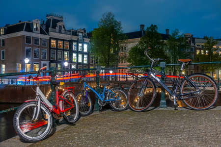 Netherlands. Night in Amsterdam. Men's, women's and children's bicycles are parked at the canal...