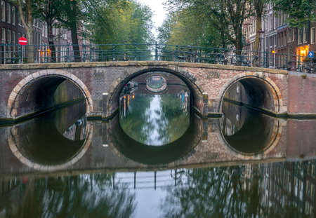 Netherlands. Morning on the Amsterdam Canal. Calm weather and a series of bridges with reflectionsの写真素材