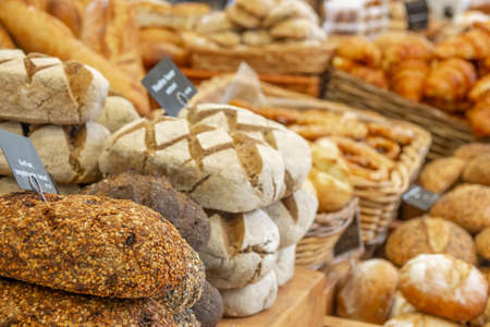 Netherlands. Farmers market in Amsterdam. Many types of breads and croissants. The sign in the foreground reads "Garlic, sun-dried tomato" in Dutchの写真素材