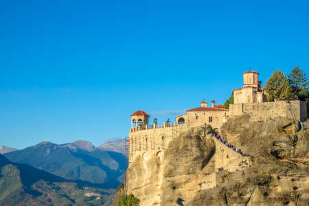 Greece. Clear summer day in Meteora. Arbor and rock monastery with red roofs against the backdrop of a mountain valleyの写真素材