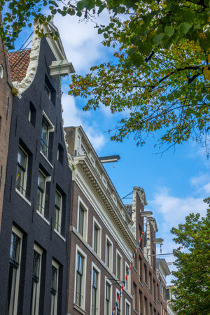 Netherlands. Sunny day in Amsterdam. Facades of authentic Dutch houses with winches on roofsの写真素材