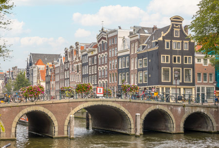 Netherlands. Old stone bridge on the Amsterdam canal. Typical Dutch houses with dancing facades on the embankmentの写真素材