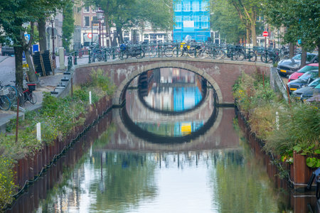 Netherlands. Summer day on a canal in the center of Amsterdam. Lots of bicycles and cars on the bridge and embankmentsの写真素材