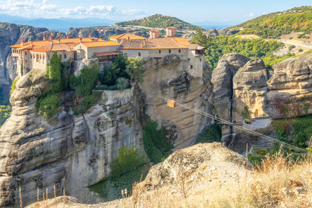 Greece. Sunny summer day in Kalambaka. Monastery with red roofs on a cliff and a cable carの写真素材
